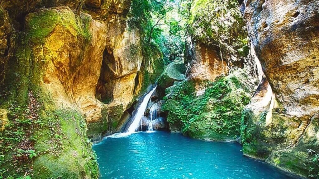 Bassin Bleu à Jacmel, Haïti, avec sa cascade et ses eaux turquoises entourées de verdure.